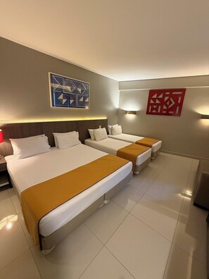 A hotel room with three beds, a red abstract wall art piece, and a geometric wall art piece. - San Diego Suítes Veredas Sete Lagoas (Sete Lagoas)