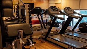 A gym with treadmills, weight machines, and a mirror. - San Diego Suítes Veredas Sete Lagoas (Sete Lagoas)