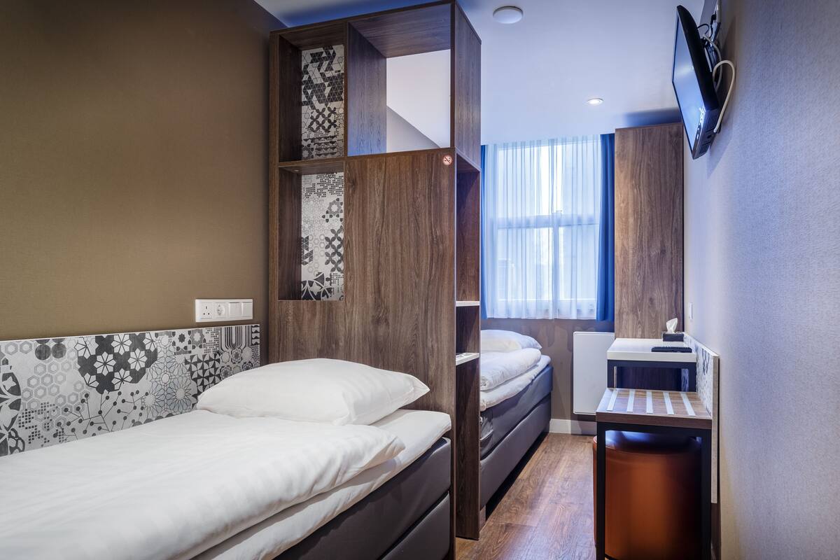 A modern hotel room with a bed, a desk, and a TV.