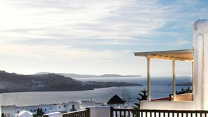 A coastal view with a white building and a clear sky. - Loukas Pension (Mykonos)