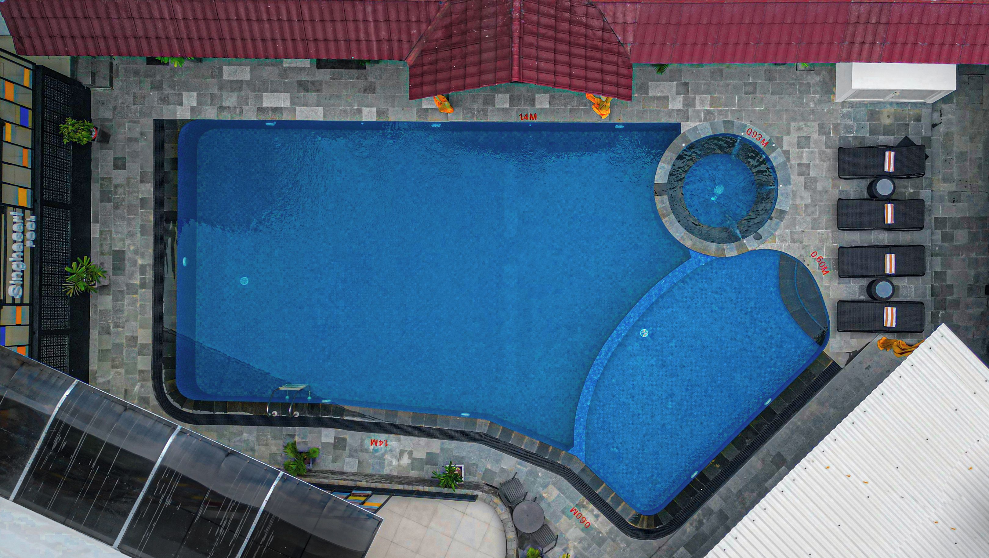Vista aérea de una piscina con un jacuzzi circular, rodeada de sillas de descanso y una pequeña zona de terraza.