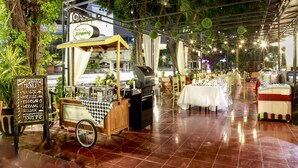 Un espace extérieur aménagé pour prendre les repas, avec un chariot de restauration, des tables et des chaises.