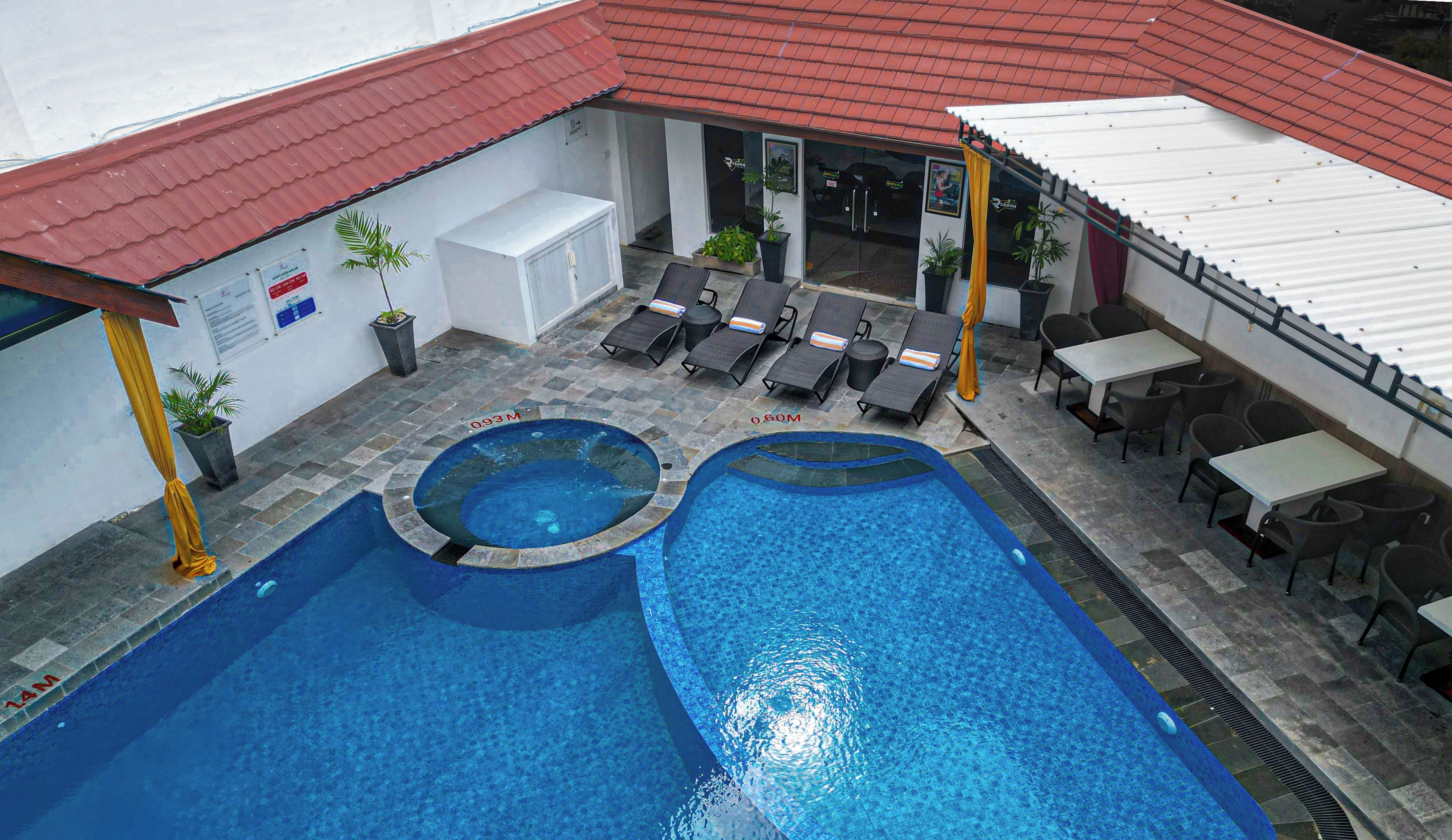 A rooftop swimming pool with two separate sections, surrounded by lounge chairs and tables.