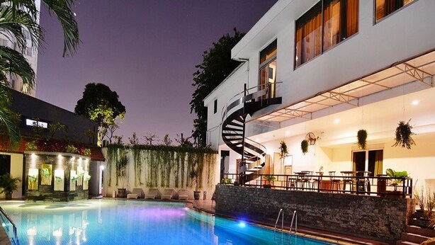 Un hôtel moderne doté d’une piscine, d’un escalier en colimaçon et d’un espace extérieur aménagé pour s’asseoir.