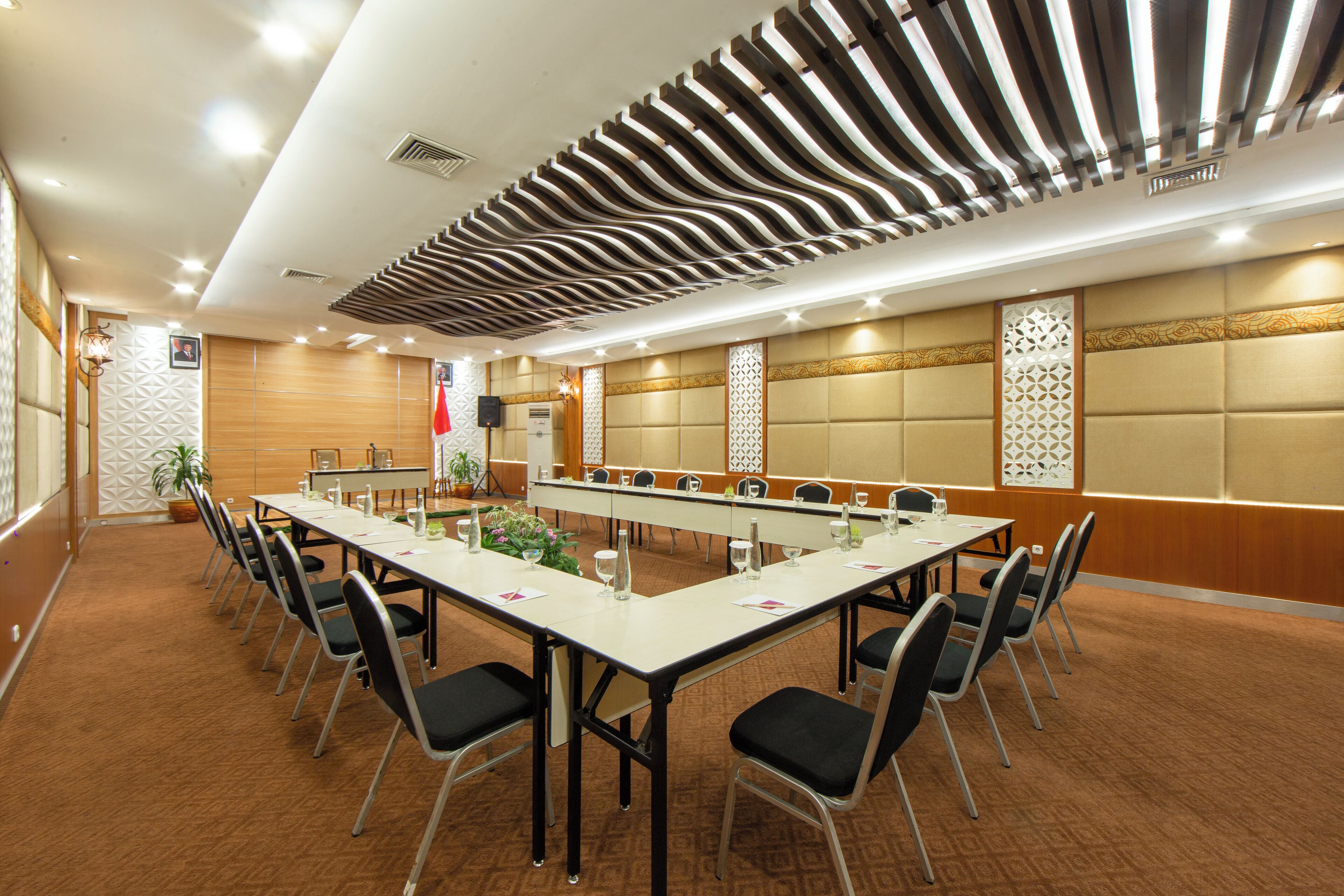 Un salón de conferencias con una larga mesa, sillas y un techo decorativo.