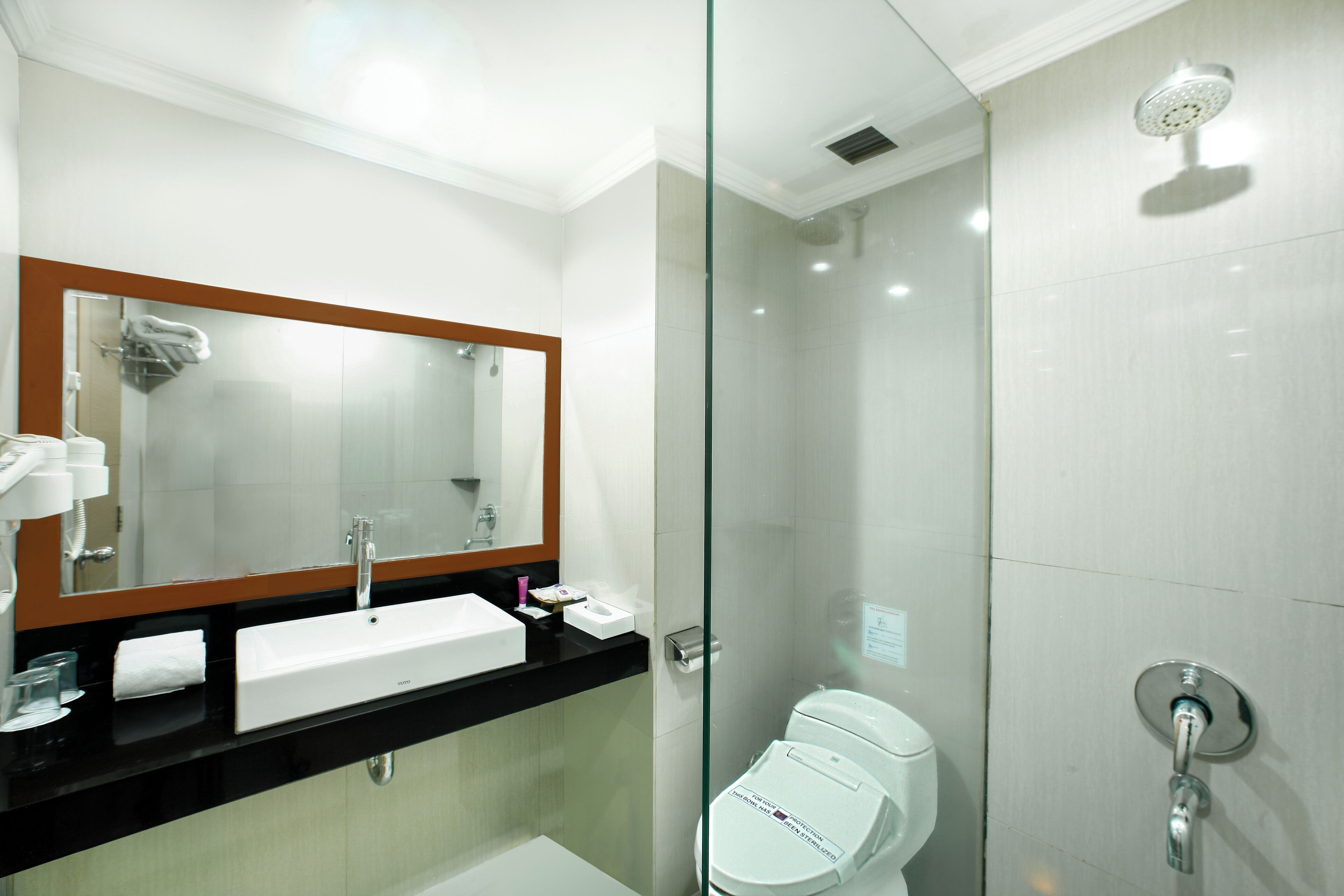 A modern bathroom with a glass-enclosed shower, a white sink, and a large mirror.