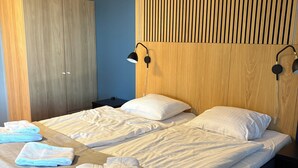 Un dormitorio con cama, dos lámparas de noche, un armario y cabecera con listones verticales.