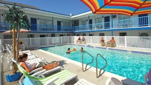 Uma área de piscina com espreguiçadeiras e um guarda-sol à beira da piscina.
