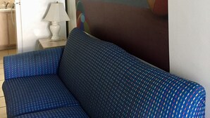 Um sofá azul com padrão em um quarto com um mural de uma cena de praia e a palavra "Wildwoods" na parede.