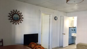 Quarto com cama, televisão, relógio e porta para um banheiro.
