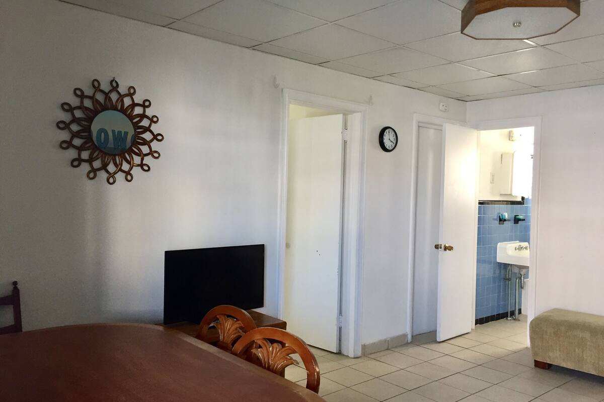 Una habitación con una cama, un televisor, un reloj y una puerta que da a un baño.