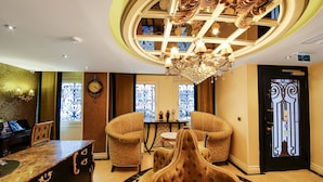 A luxurious lobby with a grand chandelier, ornate ceiling, and classic furniture.