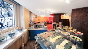A buffet area with various food options, a decorative window, and a seating area in the background.