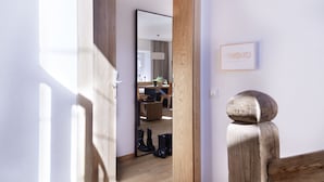 A wooden door leading into a room with a mirror reflecting a dining area.