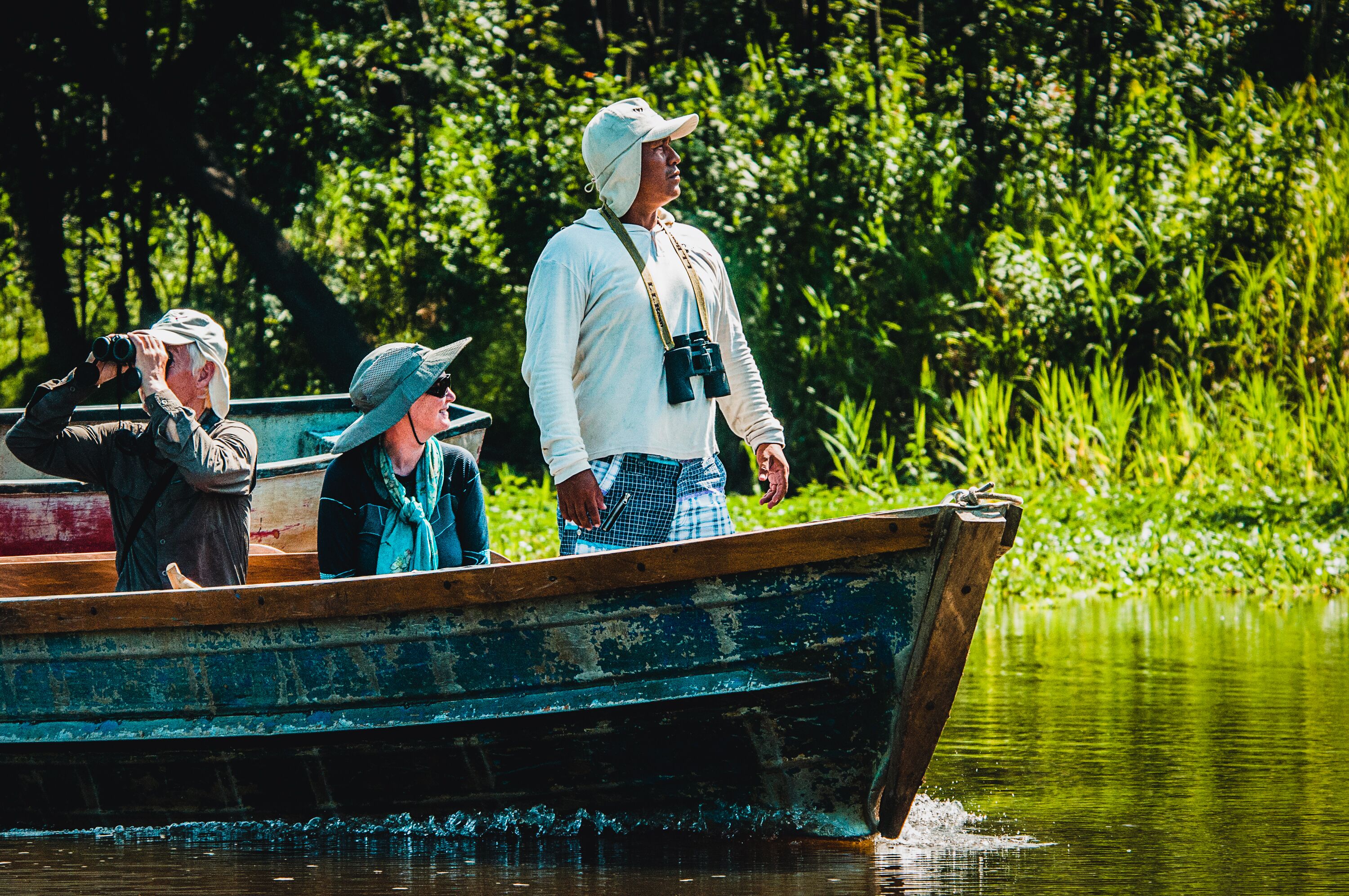 A wooden boat with three people, one taking a photo.