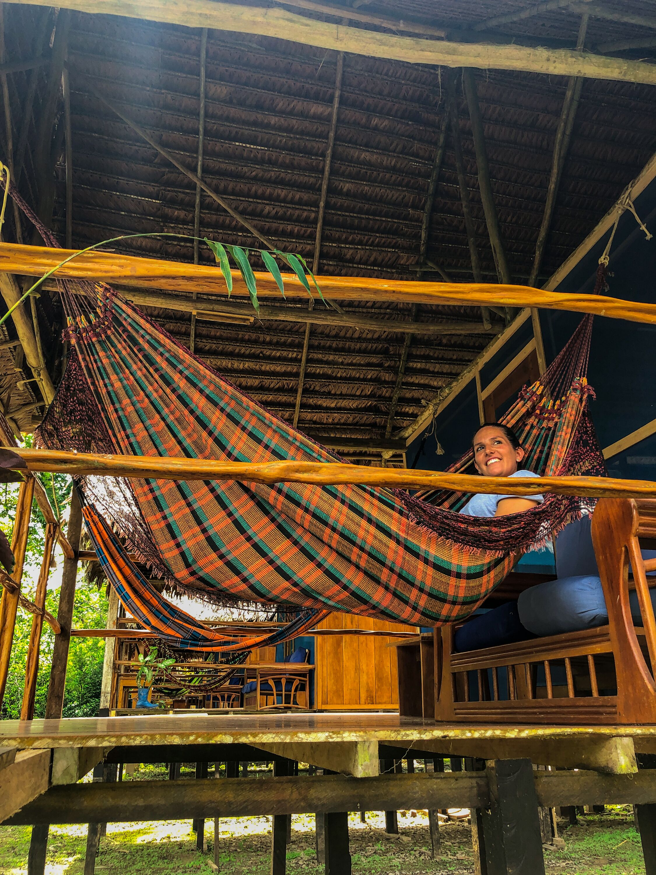 A hammock suspended between wooden beams in a rustic wooden structure.