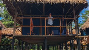 A thatched-roof structure with a wooden platform, surrounded by greenery. - Muyuna Lodge (Fernando Lores)