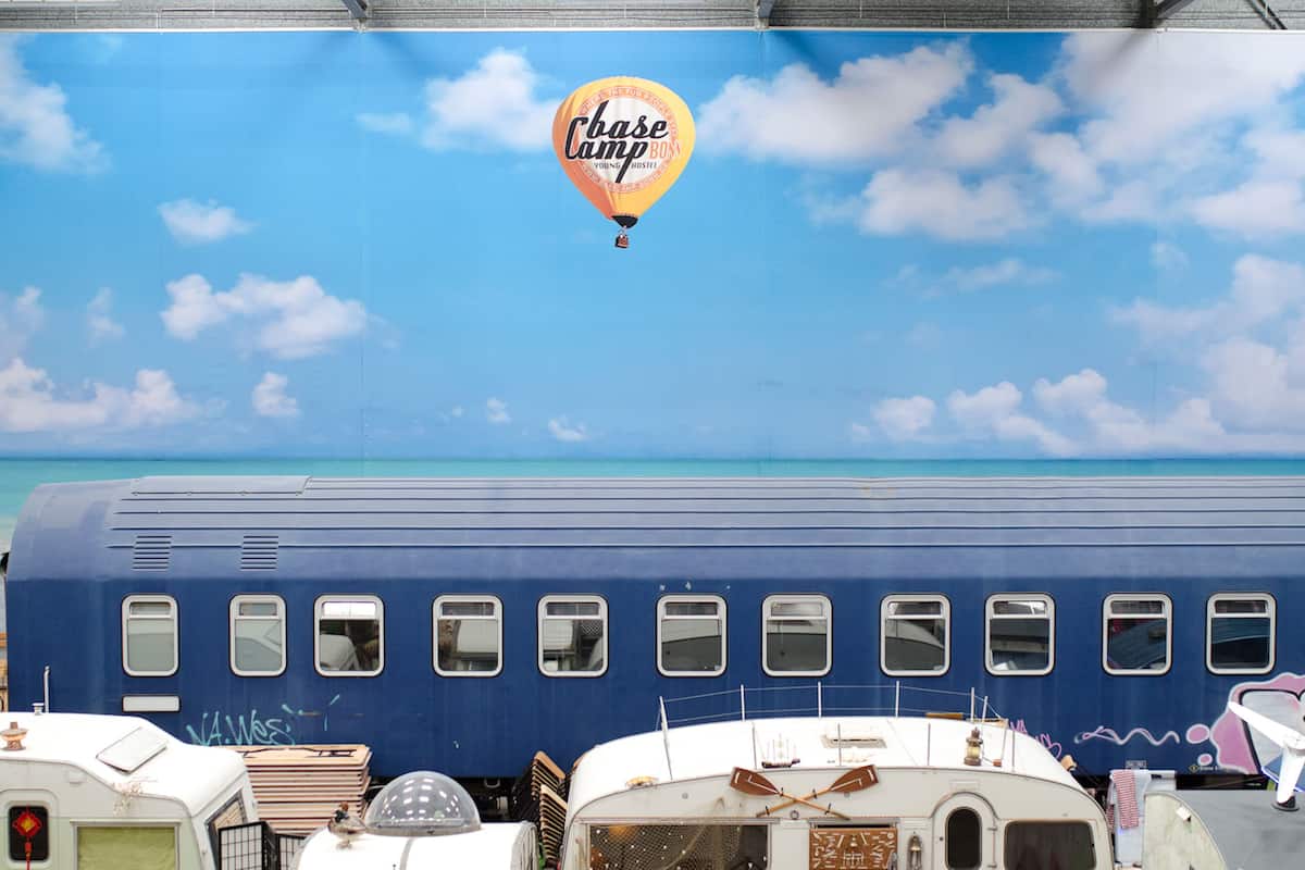 A blue train with multiple windows and a hot air balloon with "base camp" text in the sky.
