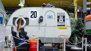 A vintage camper with a number 20 sign, a Porsche Tyres sign, and a DUNLOP tire.