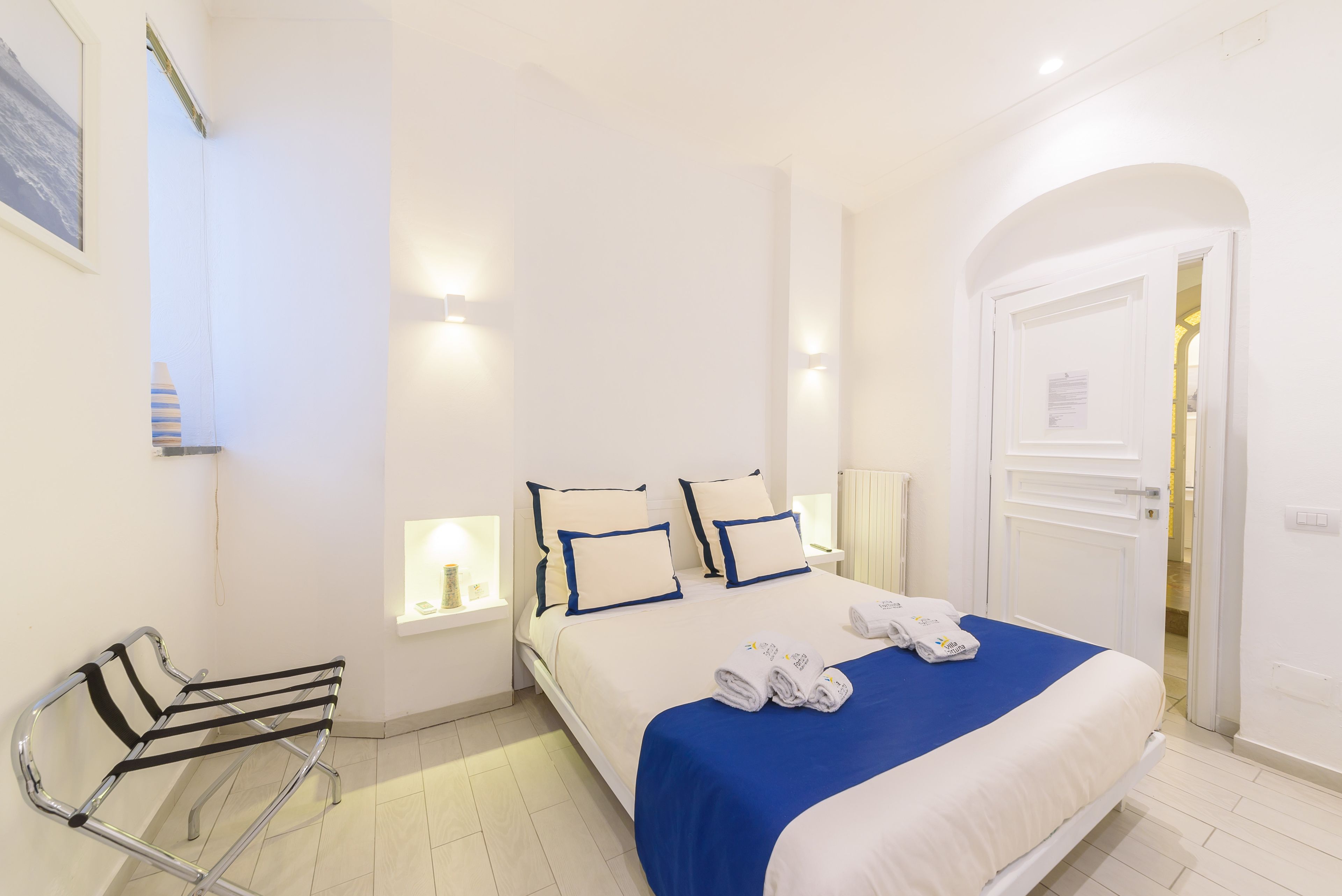 Una habitación de hotel con cama, mesitas de noche, una silla y una puerta.