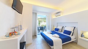 A hotel room with a bed, a TV mounted on the wall, a small table with toiletries, and a view of the outside balcony. - Villa Fortuna Holiday Resort (Ischia)
