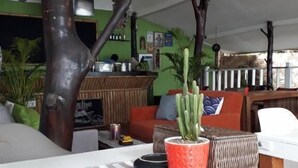 Un rincón acogedor con un gran tronco de árbol como pieza central, un sofá con cojines, una mesita de centro y un cactus en maceta.