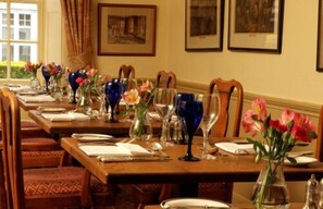 A dining area with wooden tables set for service, each with a vase of flowers and clear glassware. - Spread Eagle Hotel and Spa (Midhurst)