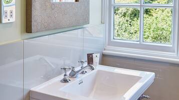 A bathroom with a large mirror, a sink, and a window with a view of greenery.