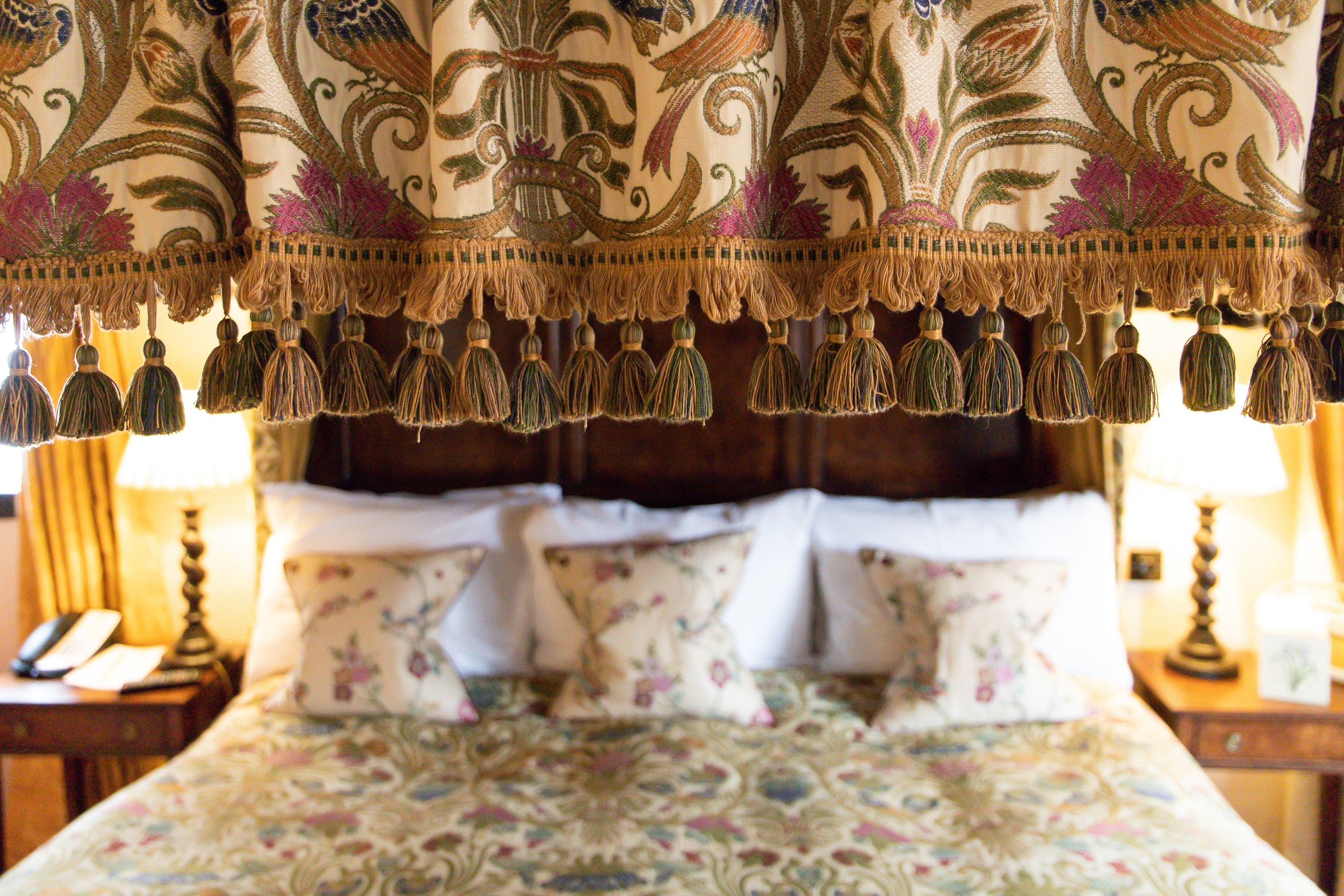 A bed with floral patterned bedding and a decorative headboard.
