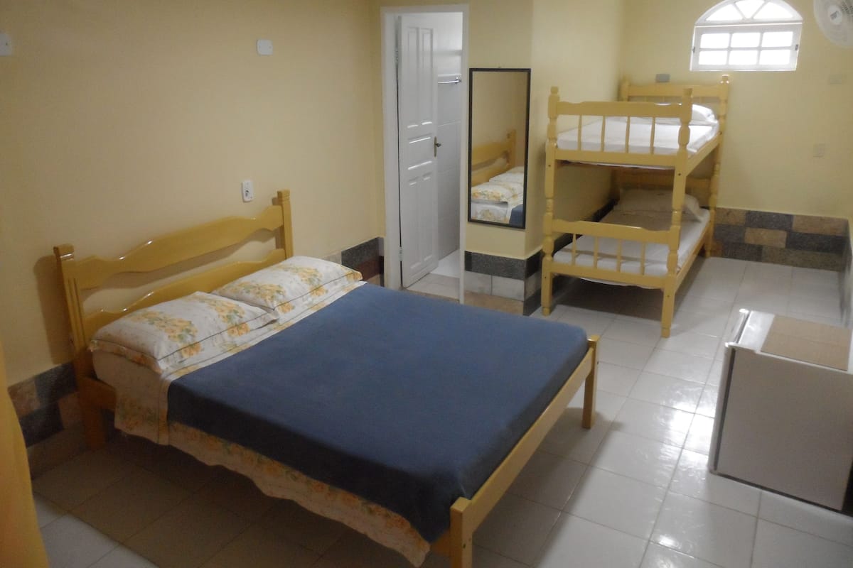 Un dormitorio con una cama individual, una litera, un espejo, una puerta y una ventana.