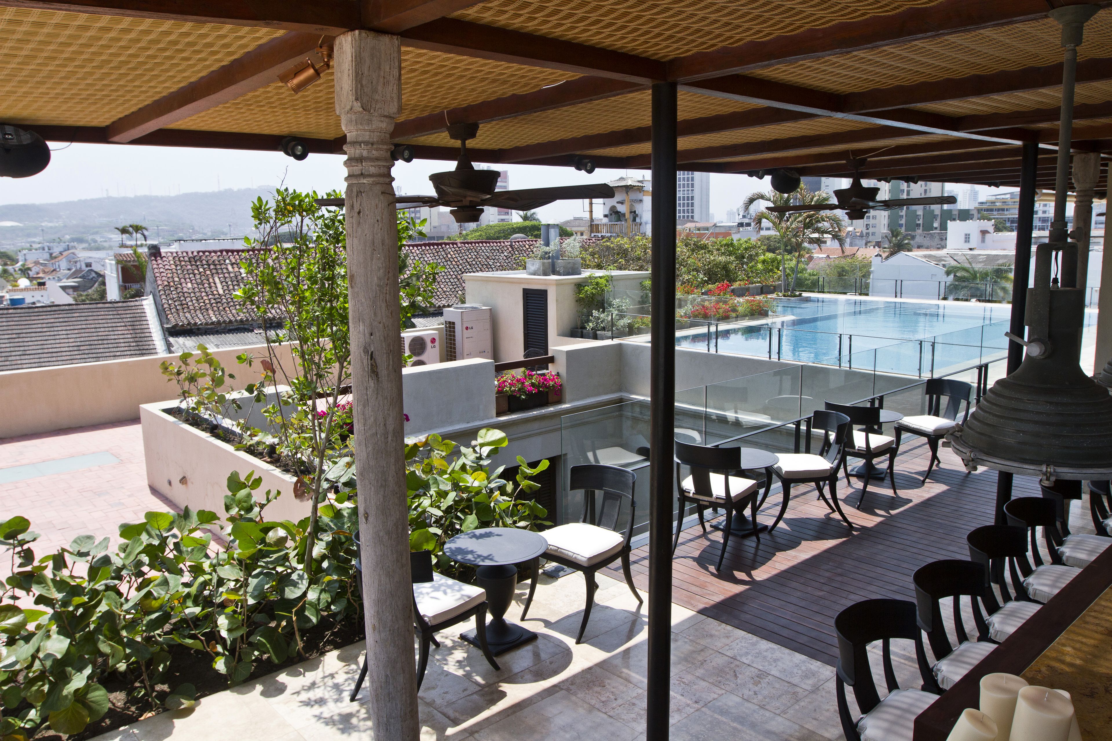 A rooftop terrace with a pool, outdoor seating, and a view of the cityscape.