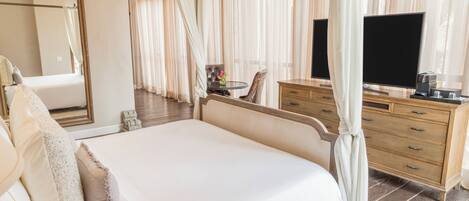 A bedroom with a large bed, a wooden dresser, a television, and a mirror.