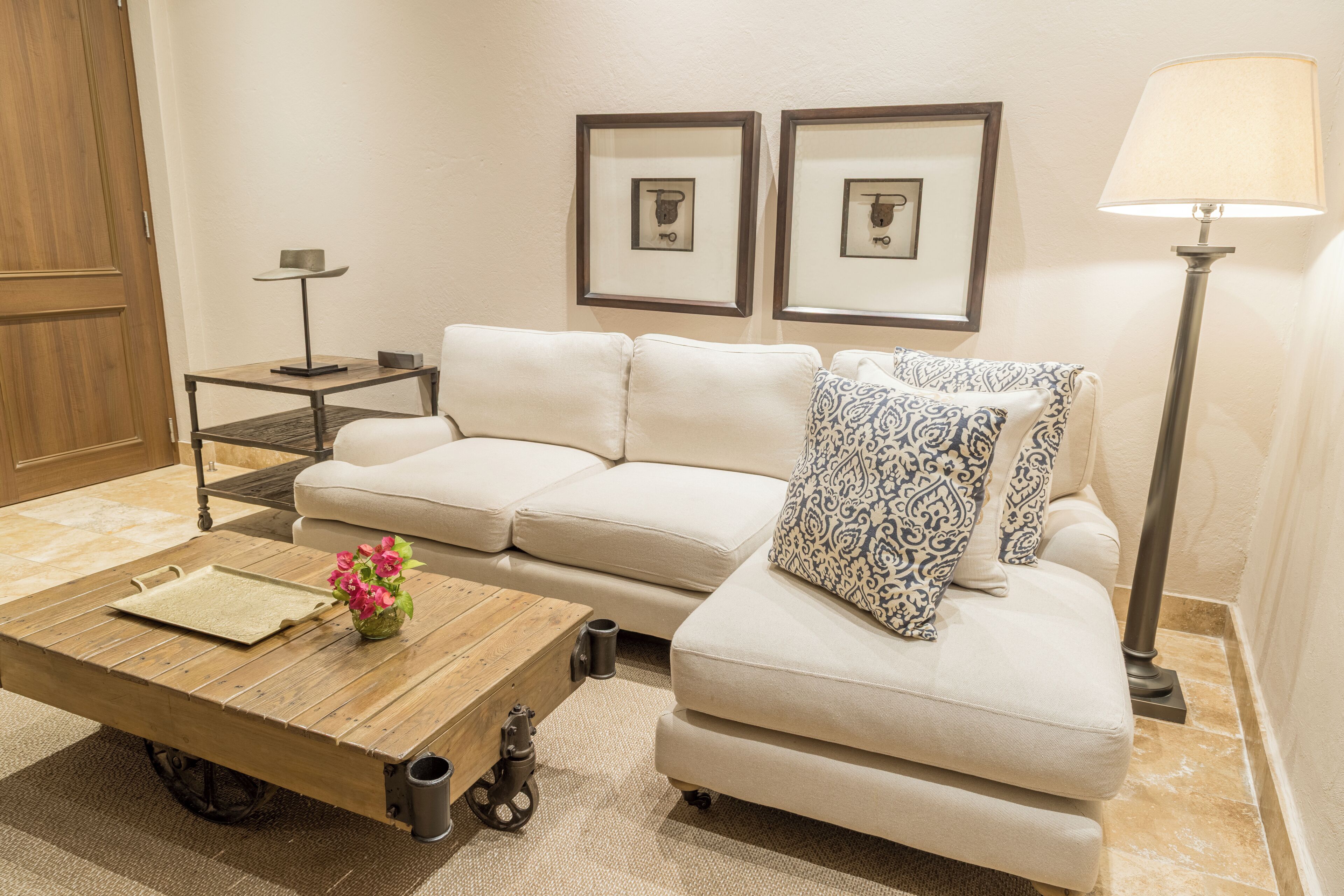 A living room with a sofa, a coffee table, a lamp, and framed pictures on the wall.