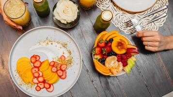 Una mesa con un plato de frutas cortadas y un vaso de jugo.