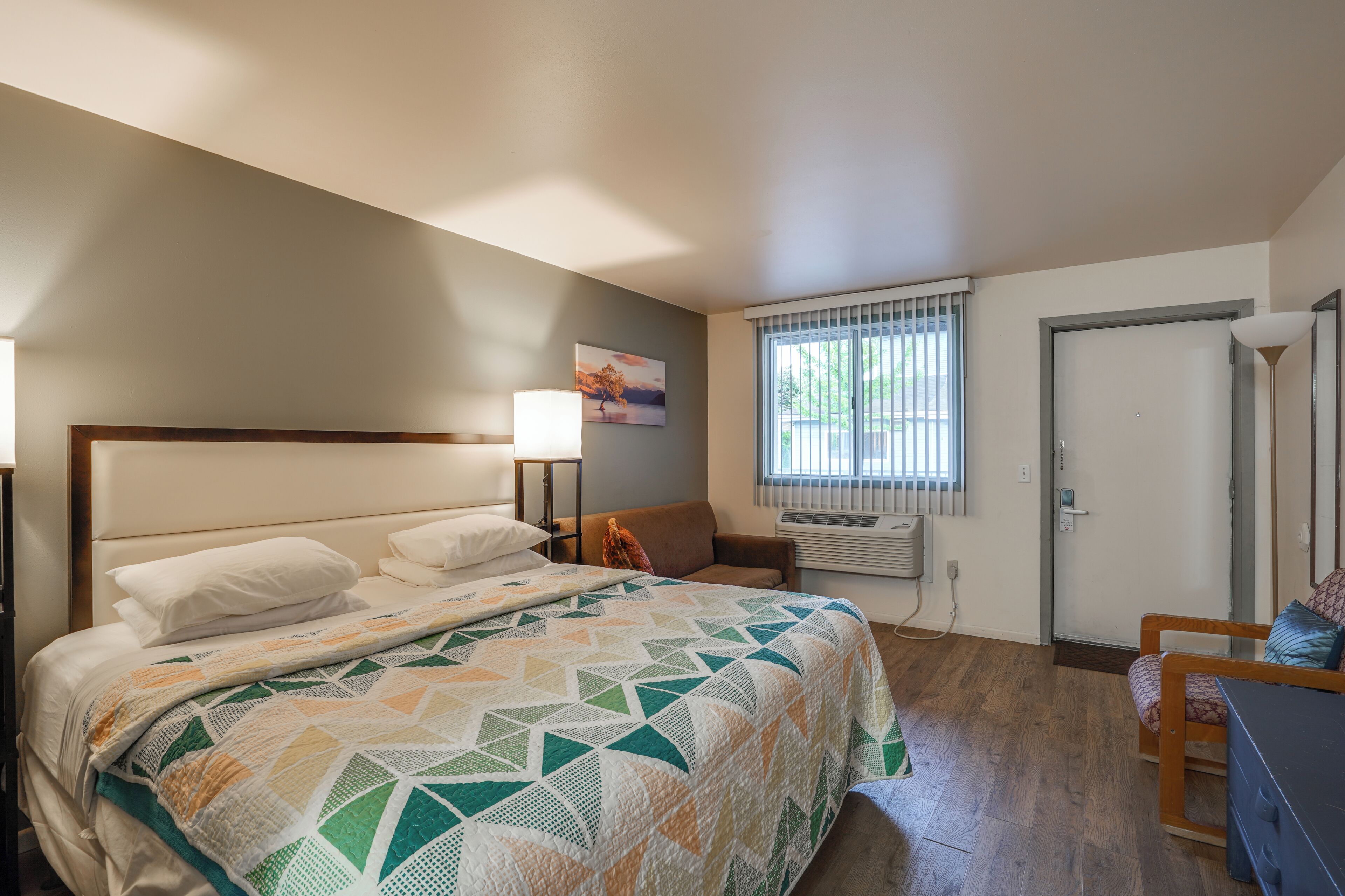 Une chambre à coucher avec un lit, une chaise, une fenêtre et une porte.