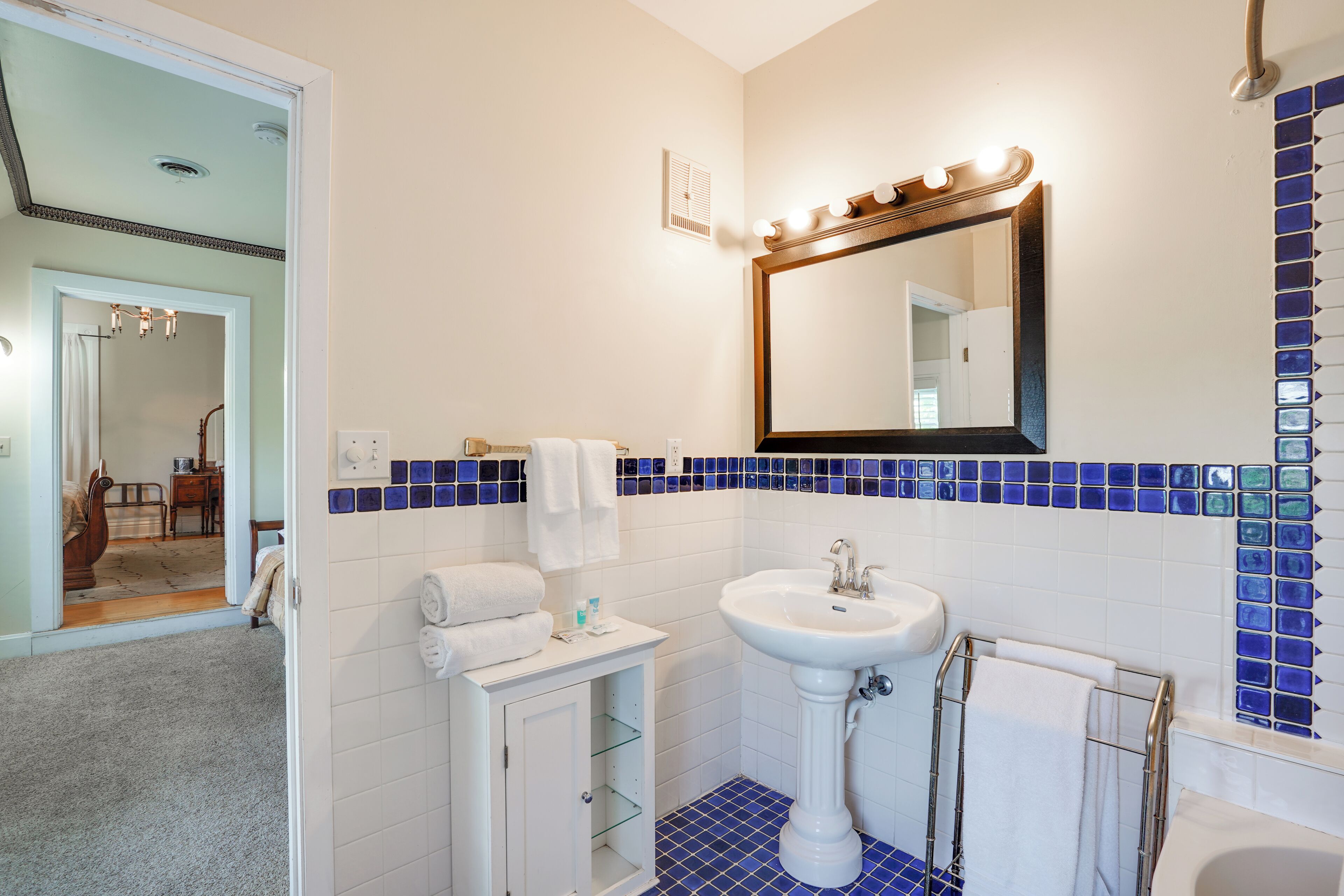 A bathroom with a sink, mirror, and blue-tiled walls.