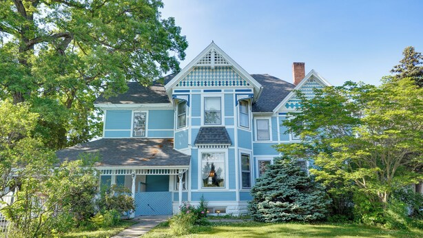 A two-story house with a porch, a chimney, and a well-maintained garden. - White Rose Inns (Wisconsin Dells)
