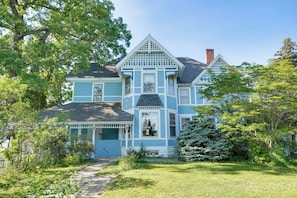 A two-story house with a porch, a chimney, and a well-maintained garden. - White Rose Inns (Wisconsin Dells)