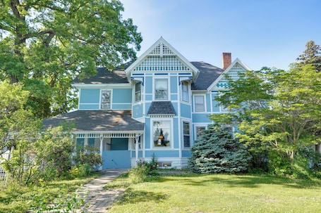 A two-story house with a porch, a chimney, and a well-maintained garden.. White Rose Inns