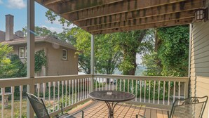 A covered outdoor area with a table and chairs, a view of a house, and a tree. - White Rose Inns (Wisconsin Dells)