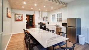 A modern kitchen with a marble island, stainless steel appliances, and a wooden ceiling. - White Rose Inns (Wisconsin Dells)