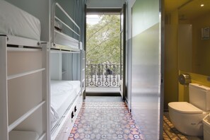 A narrow hallway with bunk beds on one side and a bathroom on the other. - Urbany Hostel BCN GO! (Barcelona)