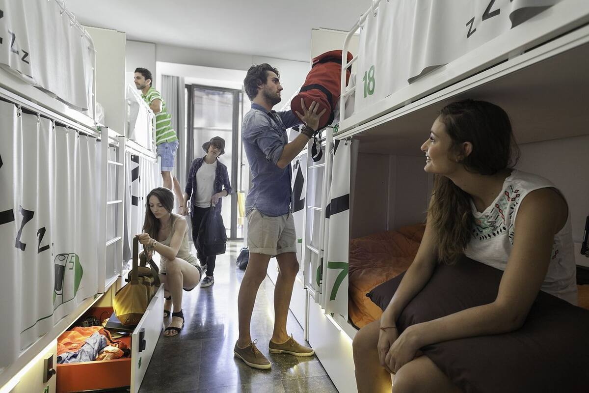 Um quarto de dormitório com beliches, um armário e uma mala no chão.
