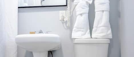A modern bathroom with a pedestal sink, a toilet, and a hand dryer.