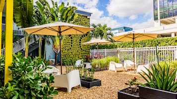 Relax in a serene outdoor patio with comfortable lounge chairs, lush greenery, and a shaded area.