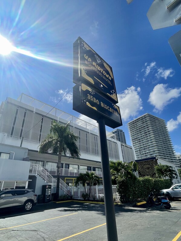 Señal del Boutique Motel, con cielo despejado y edificios altos al fondo.
