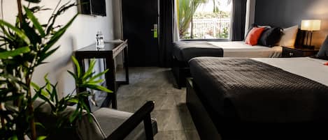 Hotelkamer met een bed, bureau, stoel, televisie en raam met uitzicht op groen.