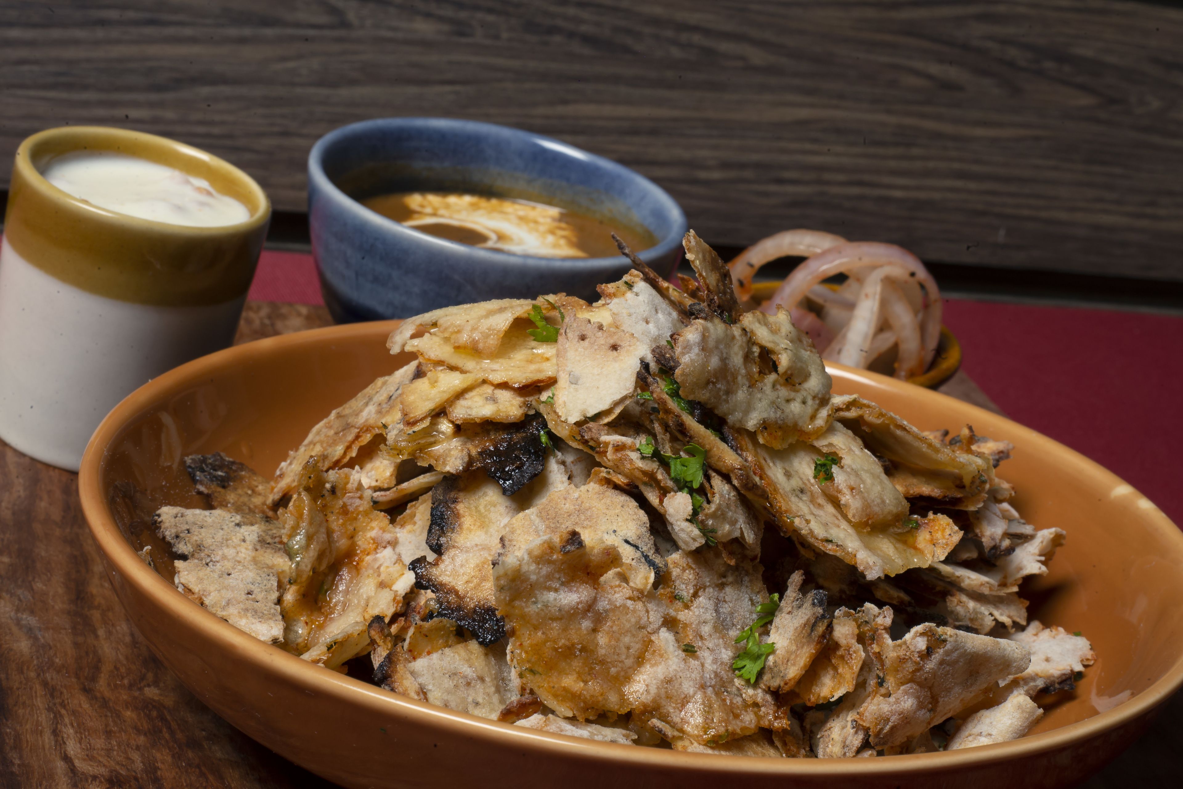 Un plato de pescado frito acompañado de salsa para mojar y un recipiente pequeño con yogur.