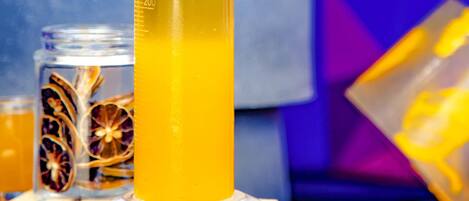 Un vaso alto con líquido amarillo, posiblemente una bebida, y rodajas de naranja deshidratada.