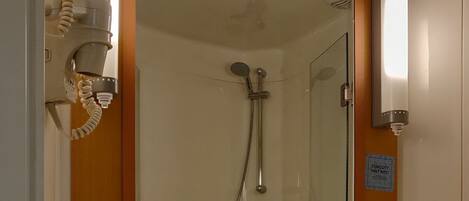 Un baño con lavamanos, espejo, toallero, ducha y cubo de basura.